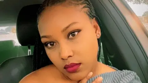 South Africa Police Service Constable Boipelo Senoge poses for a picture wearing a grey top and red lipstick.