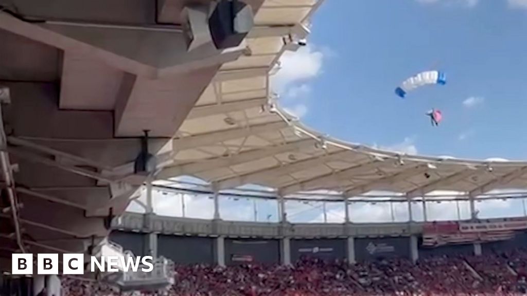 Moment parachutist left dangling on stadium roof