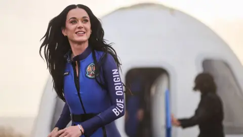 EPA Katy Perry walking away after emerging from the Blue Origin space capsule, wearing a blue Blue Origin-branded jumpsuit