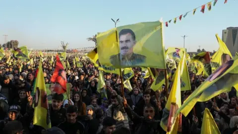 Reuters A crowd of protestors hold yellow flags featuring the face of Abdullah Ocalan.