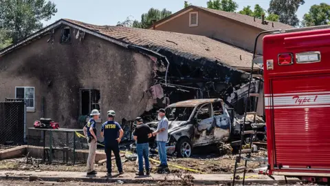 Getty Images Investigators outside a home which is heavily burned