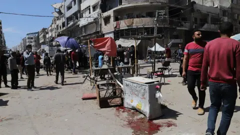 Anadolu via Getty Images Palestinians look at the aftermath of reported Israeli strikes on a restaurant and a market place on al-Wahda Street, al-Rimal neighbourhood, Gaza City, northern Gaza (7 May 2025)