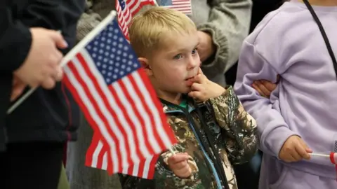 Reuters People from the first group of white South Africans granted refugee status in the US hold US flags as they attend a meet and greet event, at Dulles International Airport