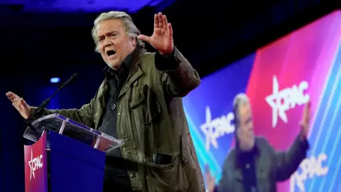 Reuters Steve Bannon in the midst of a speech in front of a large illuminated screen, waving his arms