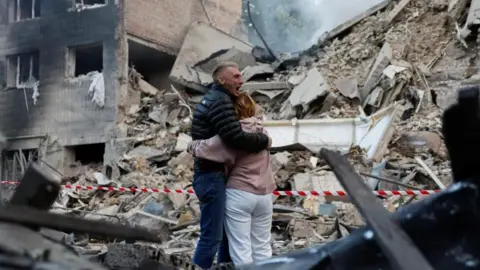Reuters Residents react at the site of an apartment building damaged during a Russian strike on Kyiv.