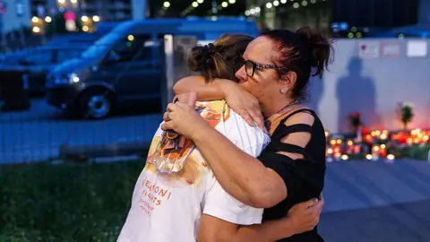 Getty Images People embrace as others light candles at the school on June 10, 2025 in Graz, Austria.