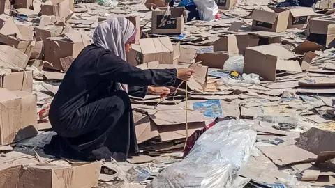 Reuters A woman pictured picking through broken cardboard boxes on the ground