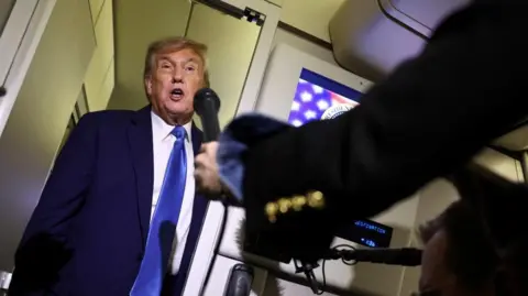 Reuters US President Donald Trump is asked questions by reporters on board Air Force One