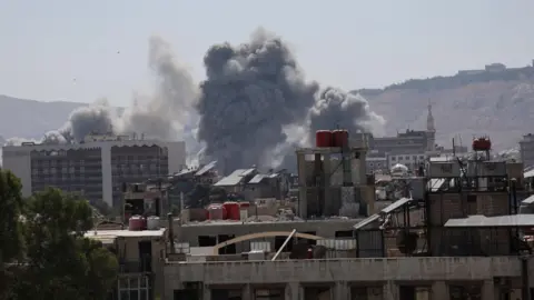 Reuters Smoke rises after an Israeli strike on Syria's defence ministry headquarters in Damascus, Syria (16 July 2025)