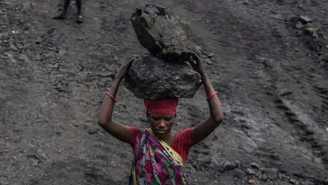 Bloomberg via Getty Images A worker wearing a colourful saree carries coal on her head at a mine in the outskirts of Dhanbad, Jharkhand, India, on Friday, Aug. 30, 2024. The Indian state of Jharkhand has passed a bill imposing mining taxes, according to people familiar with the matter, a move that's set to inflate the prices of minerals - from coal to bauxite.