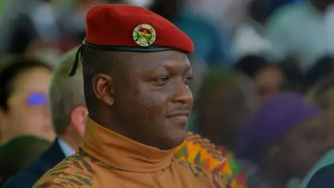 Reuters A head and shoulders shot of Burkina Faso's military leader Ibrahim Traore. He is wearing a red military beret and a camouflage roll-neck top.