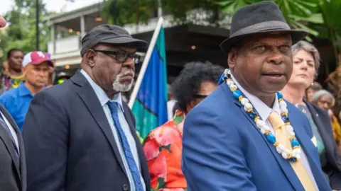 EPA Pabai Pabai, right, and Paul Kabai, both elders from the Torres Strait Islands, wearing suits and hats. Pabai is wearing a traditional necklace, made of shells. 