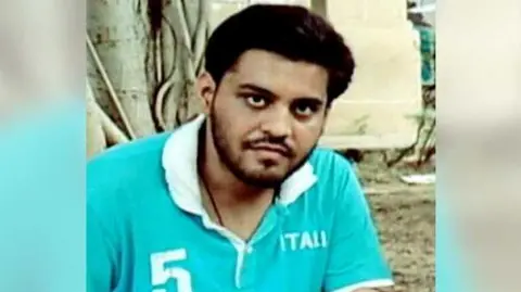 Najeeb Ahmed's family Najeeb Ahmed wearing a blue coloured t-shirt with white collars sitting in a park 