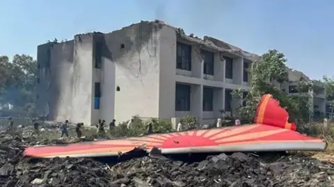 Government of India / Ministry of Civil Aviation Aircraft Accident Investigation Bureau Vertical Stabilizer adjacent to the building referenced as building A in the report. The Aircraft was destroyed due to impact with the buildings on the ground and subsequent fire. A total of five buildings, shown in the image on the right, were impacted and suffered major structural and fire damages.