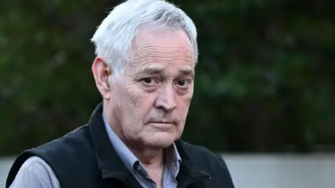 EPA Ian Wilkinson wearing a dress shirt and a black vest