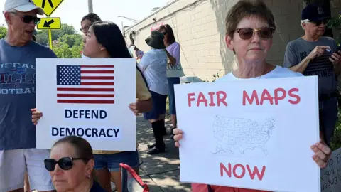 Getty Images A protester in New York holds a sign that says 'Fair Maps Now'
