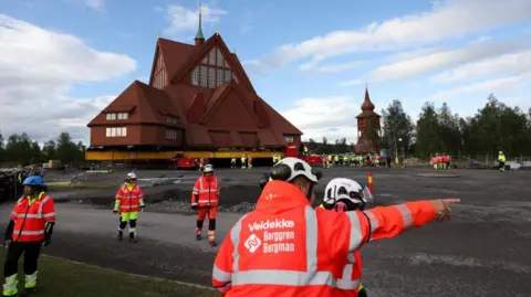 Reuters Kiruna's historic wooden church sits on a wheeled transportation unit before being moved to a new site in Kiruna, Sweden