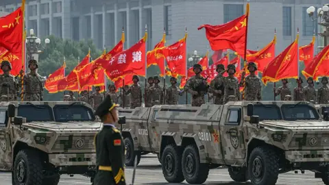 Getty Images Military vehicle have soldiers on them and red flags on top