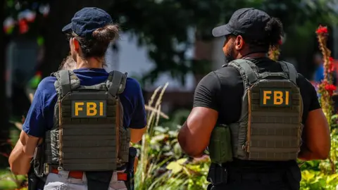 Yasin Ozturk/Anadolu via Getty Images File image of the back of two FBI agents, wearing bullet-proof vests with the writing 'FBI' in yellow