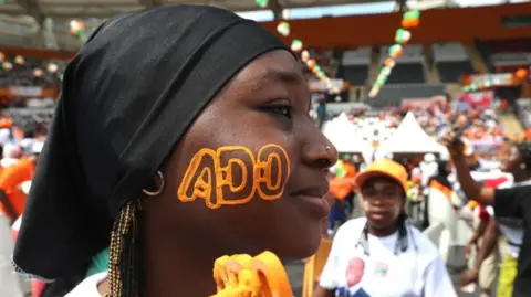 Reuters A supporter of the RHDP (Rally of Houphouetists for Democracy and Peace), the presidential party, has the initials of presidential candidate Alassane Ouattara painted on her face