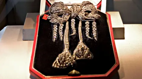 Jb Reed/Bloomberg via Getty Images The antique Empress Eugenie Brooch, an antique diamond bow brooch, pictured in a black velvet box with a red exterior. It is a lavish bow shape with trailing strands of diamonds in the shape of two large tassels, and four further strands hanging from the bow 