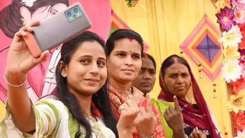 Hindustan Times via Getty Images Women voters smiling into the camera and taking a selfie after casting their votes during the Bihar Assembly Elections 2025. 