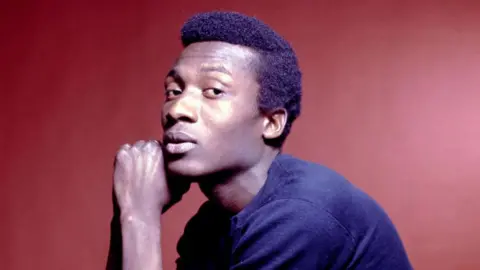 Getty Images Jimmy Cliff staring sideways at the camera, wearing a navy blue sweater.