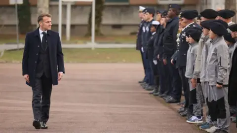 EPA French President Emmanuel Macron reviews troops and students of an army high school prior to his speech to unveil a new national military service plan at the military base in Varces