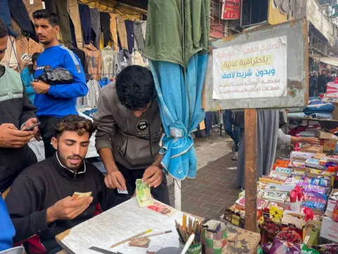 BBC Baraa Abu al-Aoun repairing banknotes at a market in Gaza City