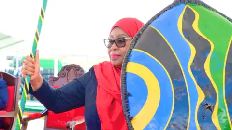 Tanzania Presidential Press Unit via Reuters Tanzania's President Samia Suluhu Hassan holds a spear and a shield during her swearing-in ceremony in Dodoma, Tanzania - 3 November 2025.