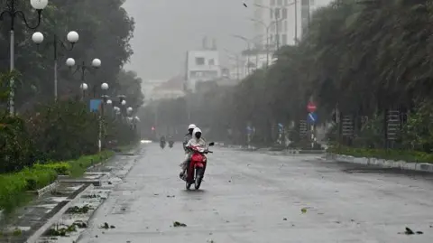 Getty Motorists can be seen riding on a scooter in strong winds ahead of the arrival of Typhoon Kalmaegi on a road near Quy Nhon beach in Gia Lai province in central Vietnam on 6 November 6, 2025