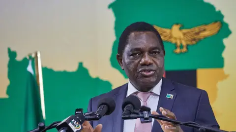 AFP via Getty Images A head and shoulders image of Hakainde Hichilema speaking. A golden eagle from the Zambian flag can be seen behind him.