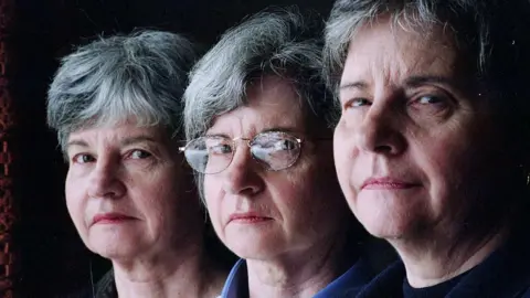 Toronto Star via Getty Images close-up of the faces of three women, the woman in the middle is wearing glasses and the three all have short grey hair