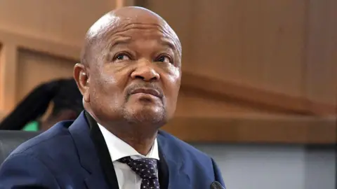 Gallo Images via Getty Images A head and shoulders image of Senzo Mchunu in a blue jacket and tie. He is glancing upwards towards his right.