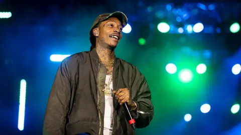 Getty Images Wiz Khalifa wears a vest and jacket with a big chain on stage at Loud Park  in Mumbai 