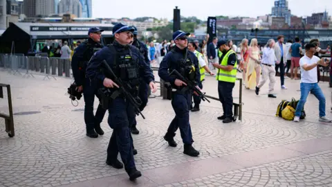 Getty Images Five armed police holding guns and wearing black uniforms. 