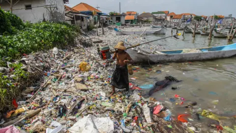 Getty Images A fisherman arrives at the beach full of rubbish that mostly consists of plastics thrown by local residents and brought by sea currents from various locations in the Kwanyar district, Bangkalan, Madura Island of Indonesia 