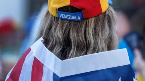 EPA/Shutterstock A person wearing a Venezuelan hat and a US flag attends a demonstration in support of US military actions in Venezuela, in Florida, USA, 04 January 2026