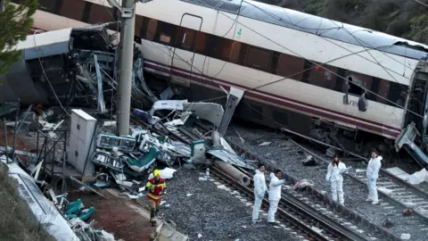 Reuters A firefighter and members of the Spanish Civil Guard work next to one of the trains involved in the accident