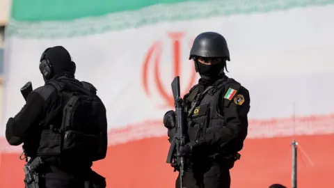 Reuters Armed Iranian security personnel watch over a pro-government rally in Tehran, Iran (12 January 2026)